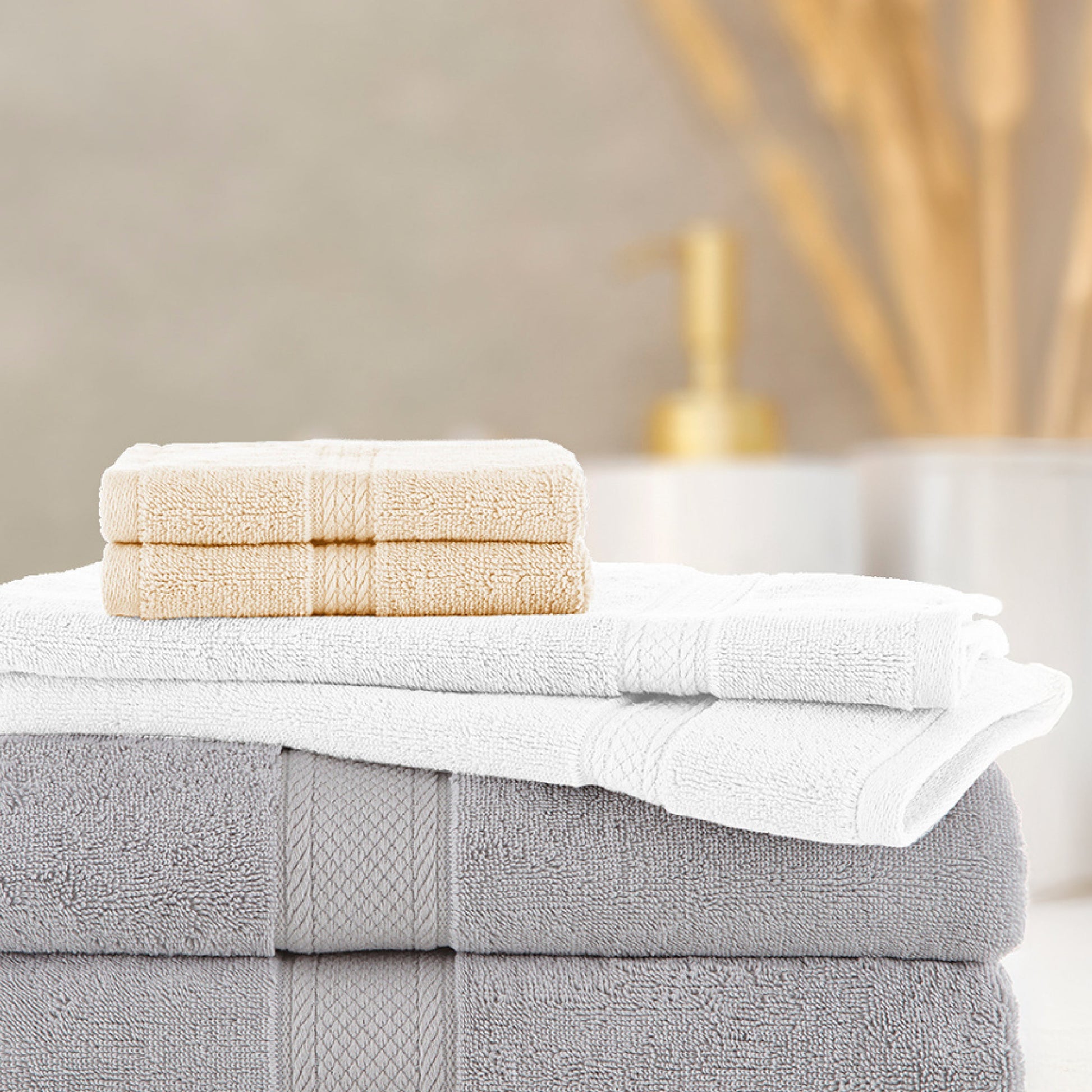 Stack of folded towels with a bar of soap on a neutral background