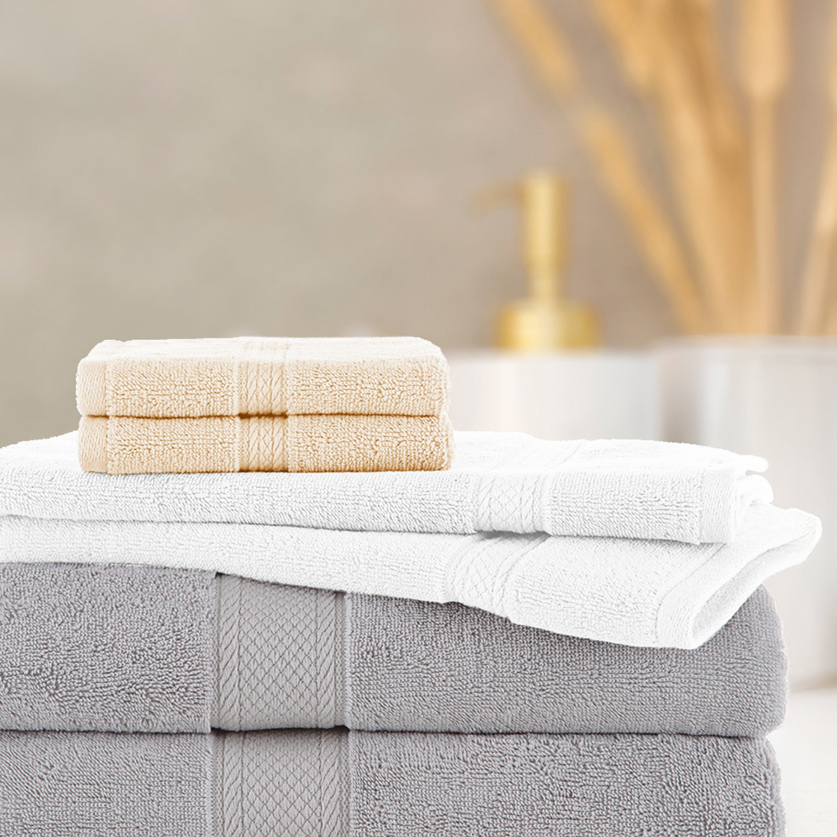Stack of folded towels with a bar of soap on a neutral background