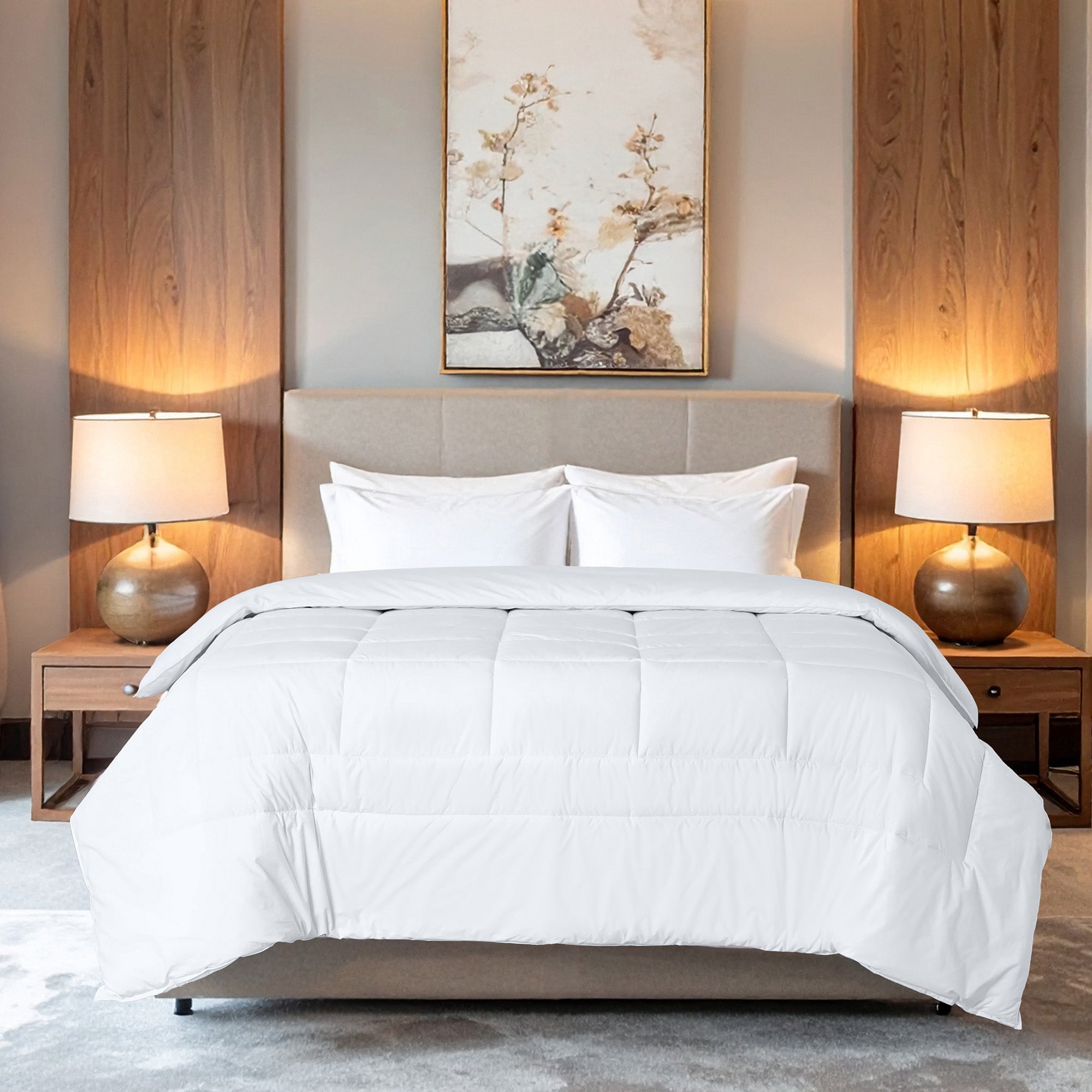 White comforter on a bed in a bedroom with lamps and artwork.