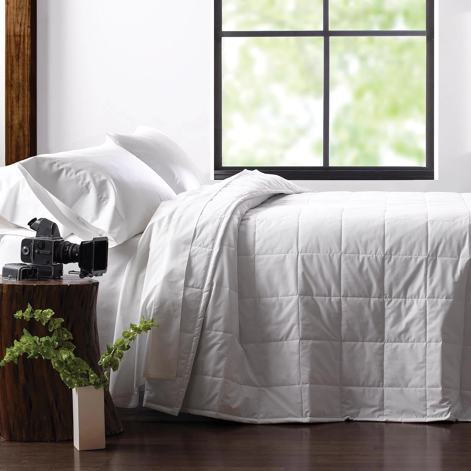 White comforter on a bed with a window in the background