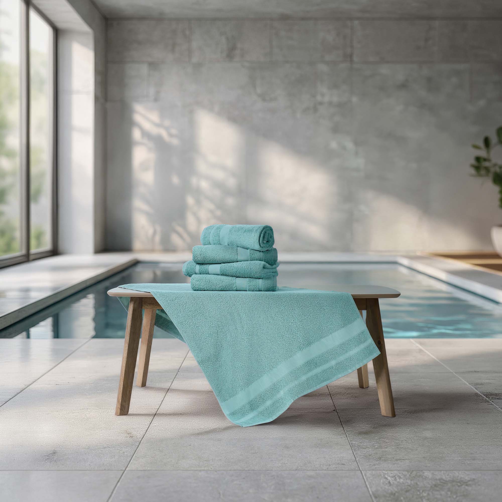 Stack of teal towels on a wooden table by a poolside.